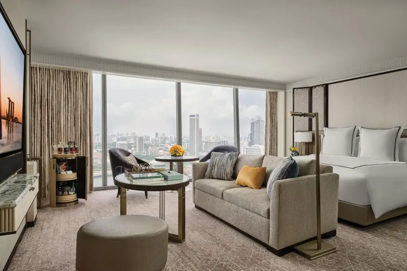 Espace de séjour lumineux avec canapé, fauteuils et vue sur la ville.
