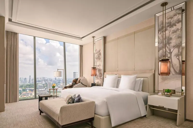 Une chambre lumineuse avec un grand lit et une vue sur la ville.