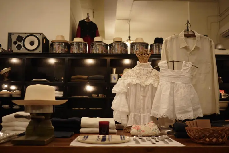 Présentation de vêtements et d'accessoires sur des étagères et une table en bois.