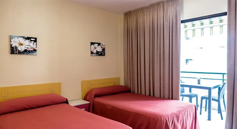 Une chambre avec deux lits et un accès à un balcon.