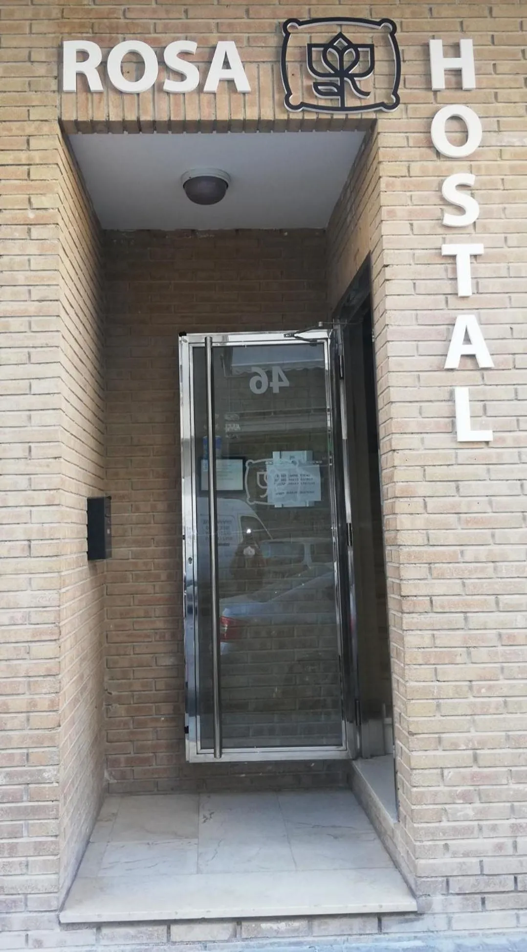 Entree d'un batiment avec une porte vitree et un auvent.