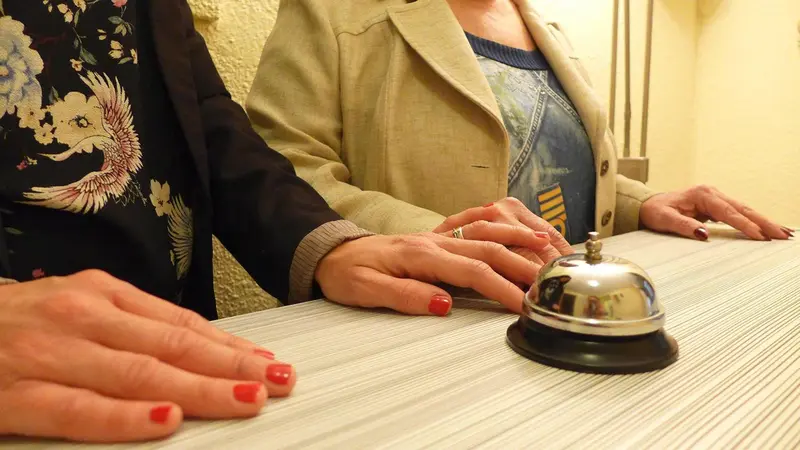 Des mains posées sur un comptoir d'accueil avec une cloche.
