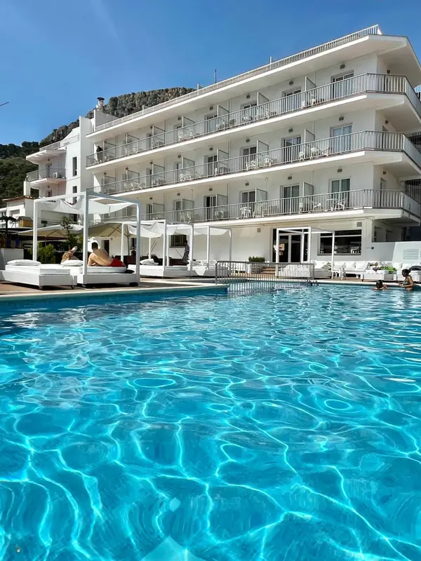 Bâtiment blanc avec des balcons surplombant une piscine bleu clair.