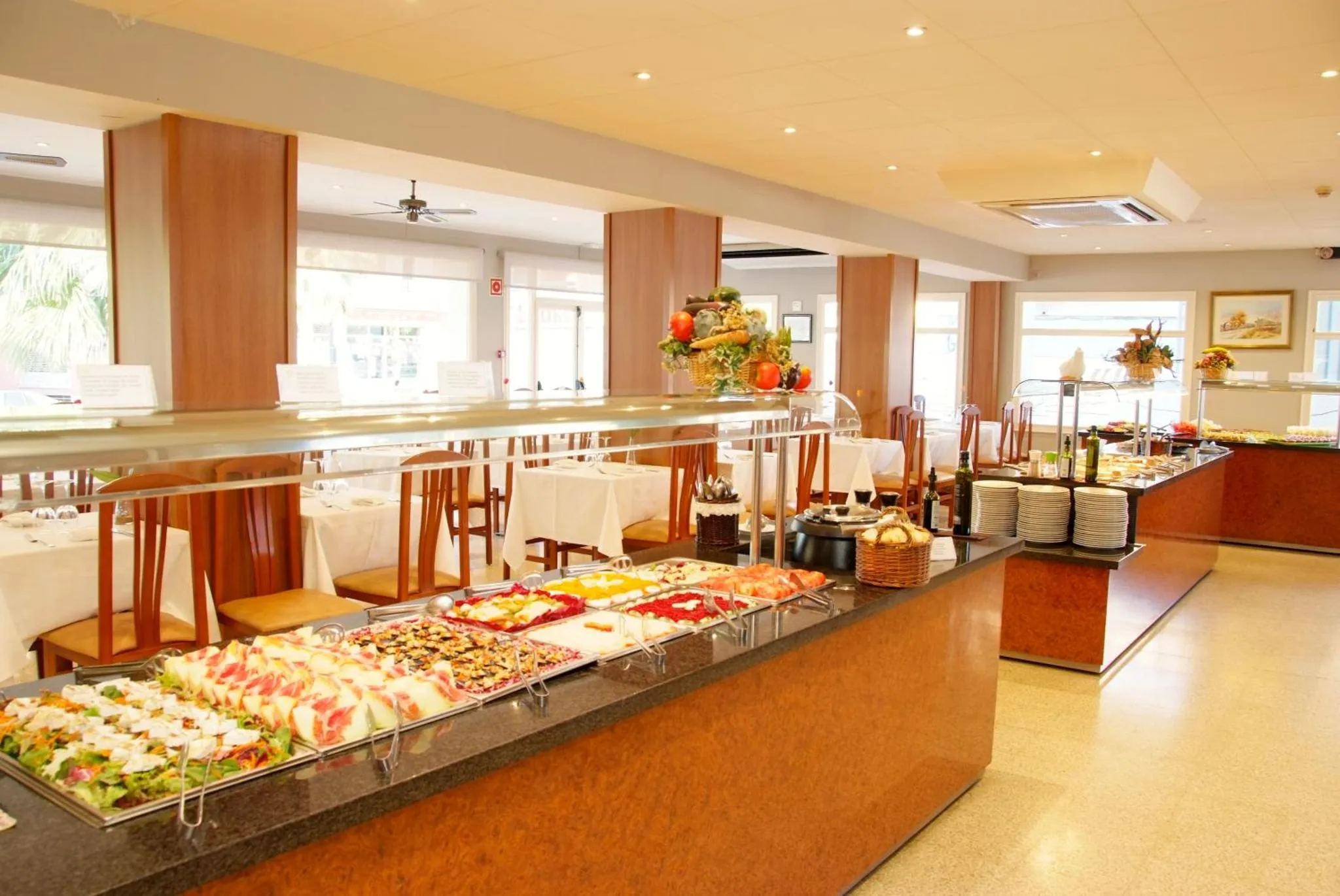 Un buffet propose une grande variété de plats et de desserts dans une salle lumineuse.