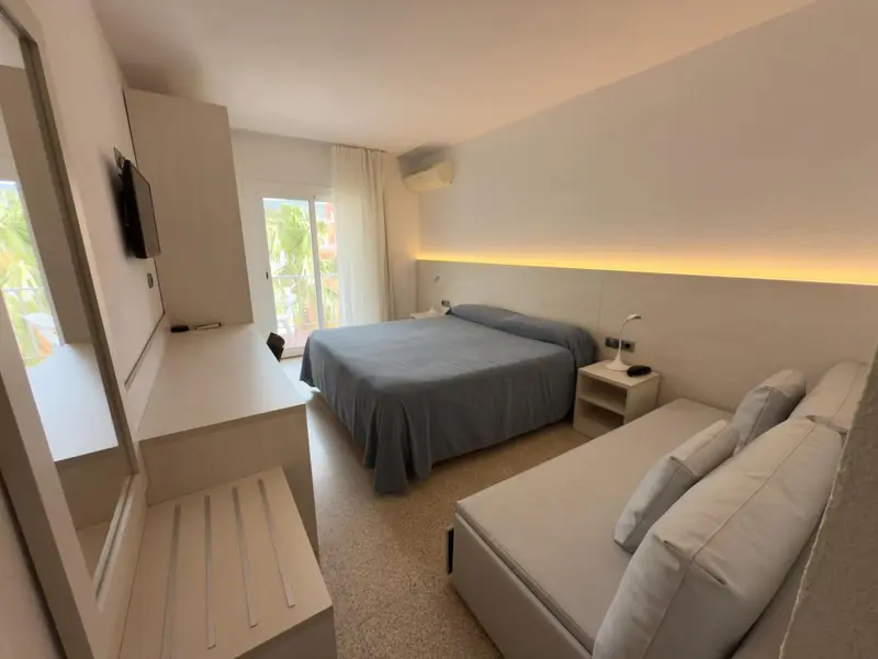 Une chambre lumineuse avec un lit double et un coin salon.