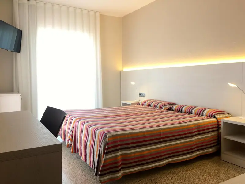 Une chambre lumineuse avec un grand lit et des lampes de chevet.