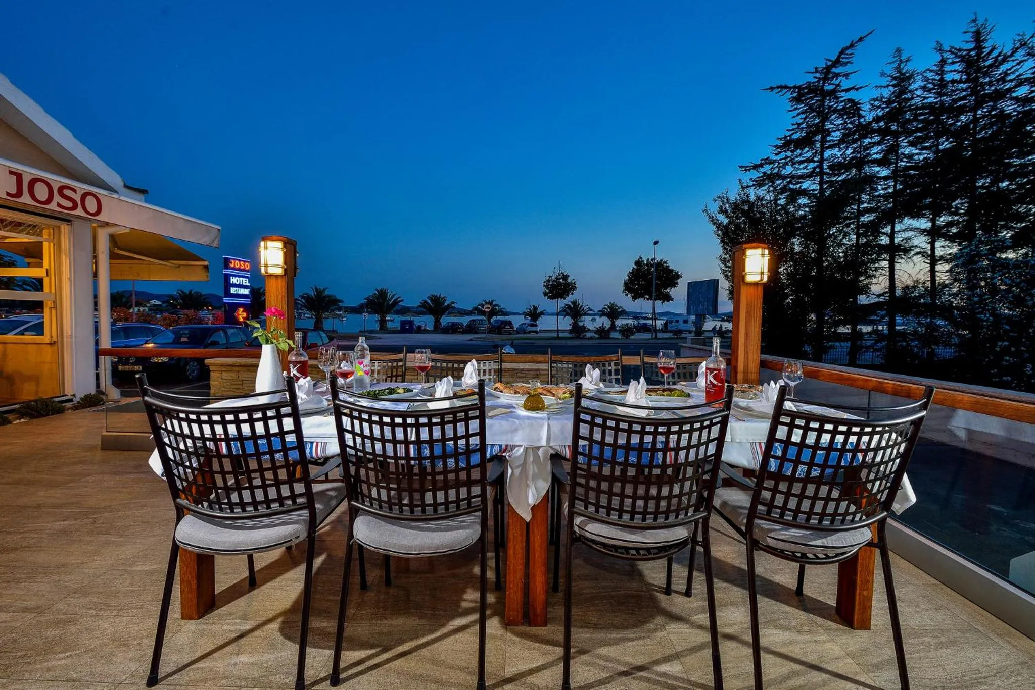 Une table dressée pour un repas en extérieur avec vue sur la mer au crépuscule.