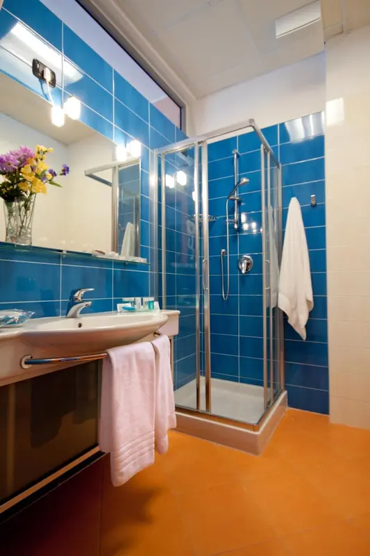 Une salle de bain lumineuse avec douche à l'italienne et carrelage bleu.