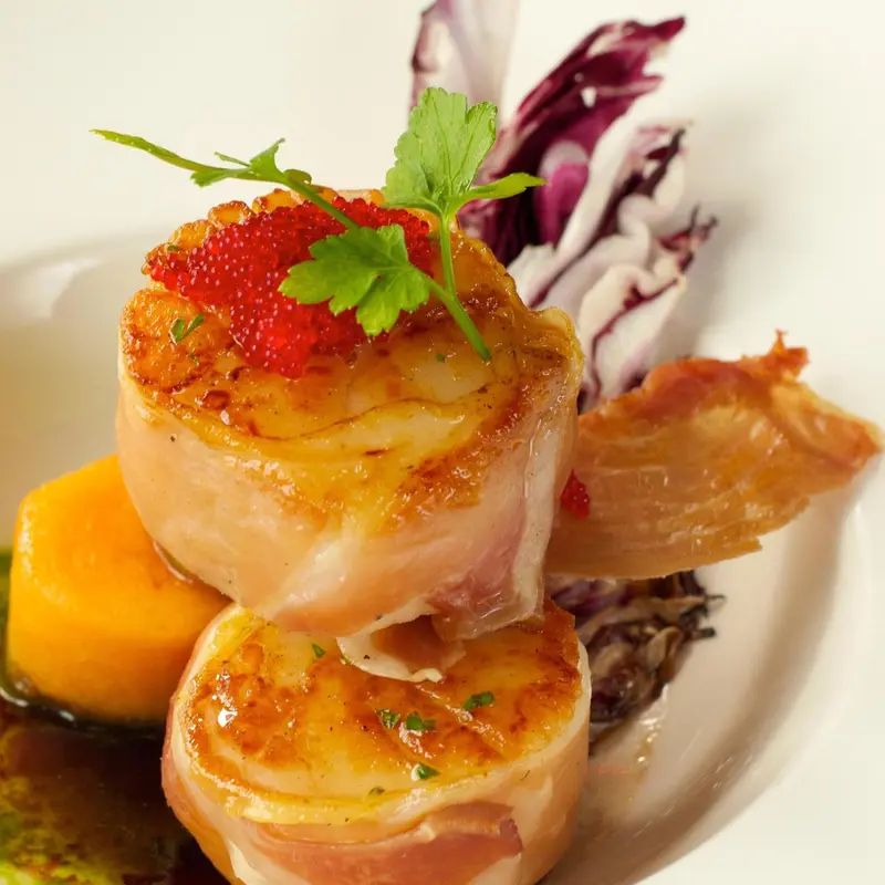 Assiette raffinée ornée de fruits de mer et d'une sauce colorée.