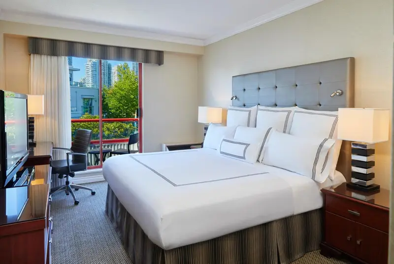 Une chambre lumineuse avec un grand lit et un bureau près d'une fenêtre.