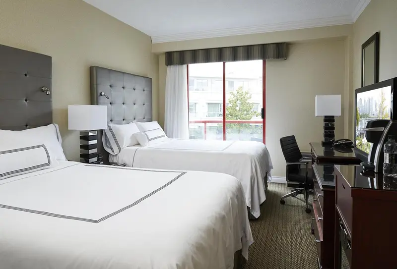 Une chambre d'hôtel lumineuse avec deux lits simples et un bureau.