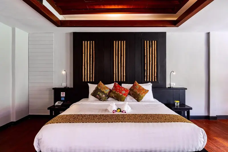 Une chambre avec un grand lit recouvert d'une courtepointe blanche et de coussins décoratifs.