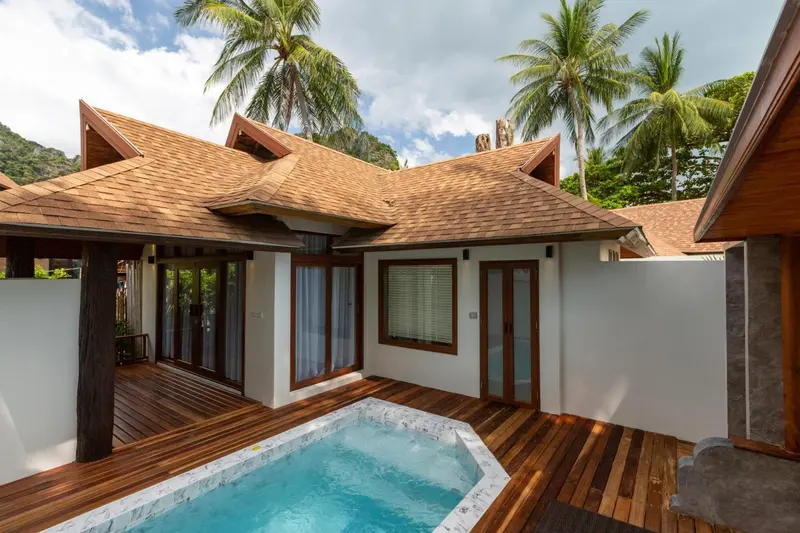 Bâtiment à toit de chaume avec une petite piscine devant.