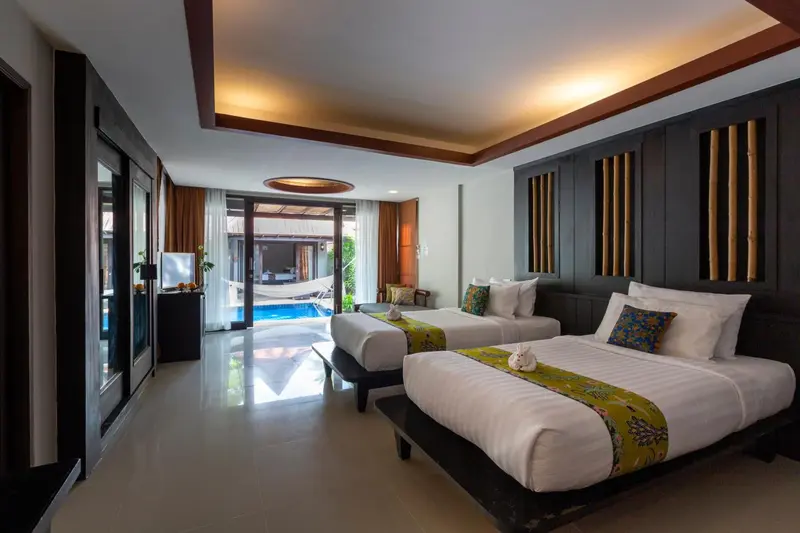 Chambre lumineuse avec deux lits simples et vue sur une piscine.