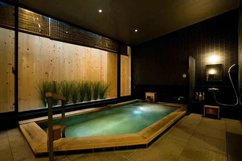 Bassin intérieur en bois avec jets d'eau et éclairage tamisé.