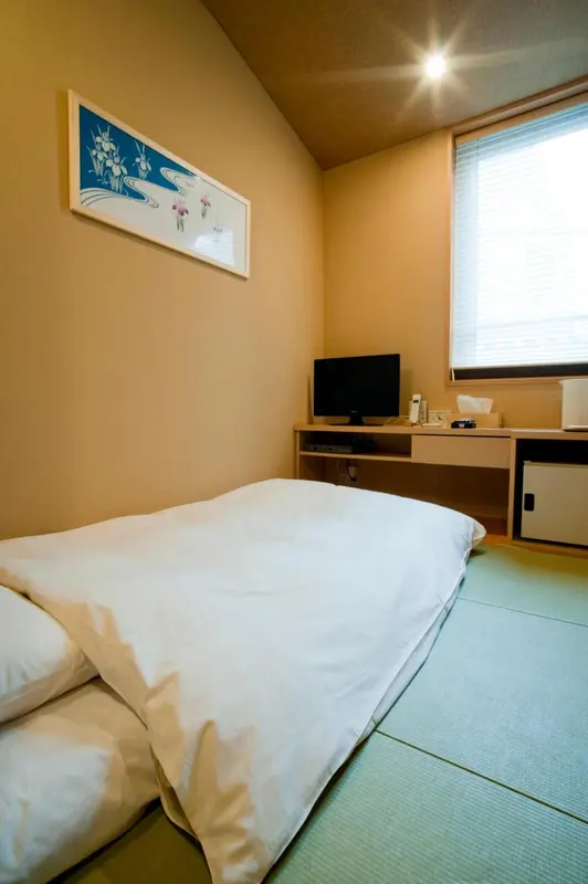 Une chambre lumineuse avec un lit simple et un bureau.