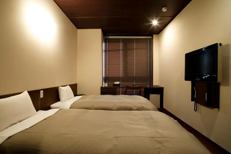 Une chambre lumineuse avec deux lits simples et un bureau.