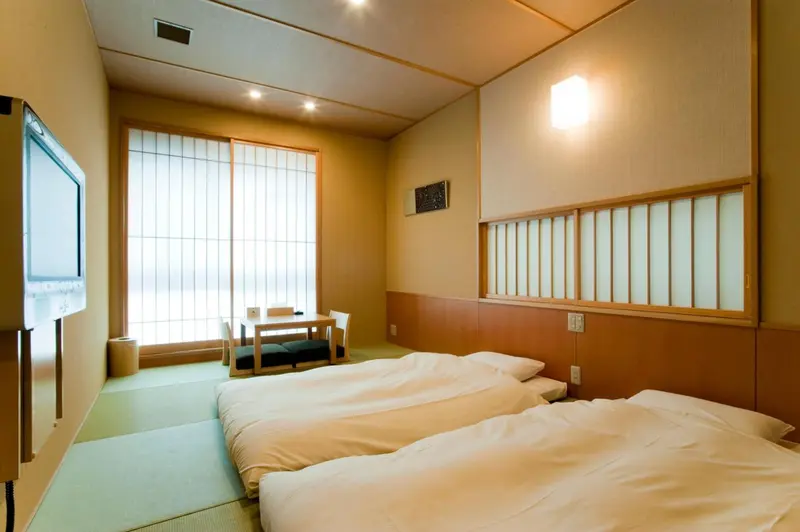 Une chambre lumineuse avec deux lits simples et une table basse près d'une fenêtre.