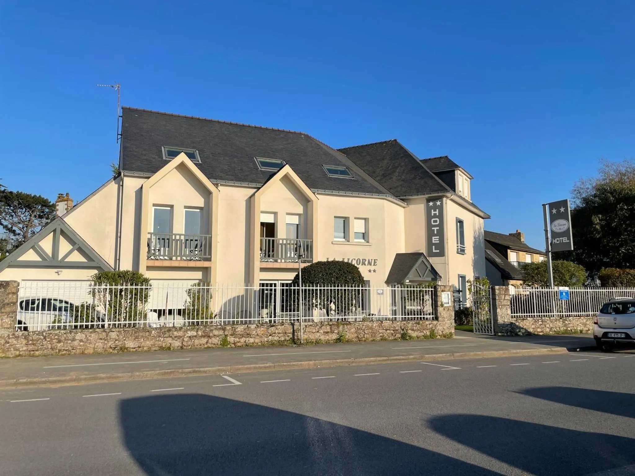 Façade d'un bâtiment blanc avec des fenêtres et un jardin devant.