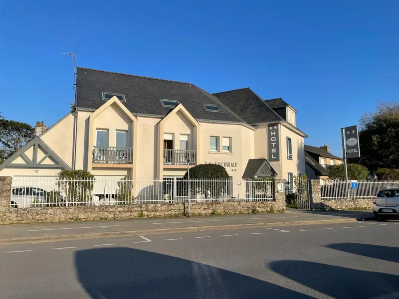 Façade d'un bâtiment blanc avec des fenêtres et un jardin devant.