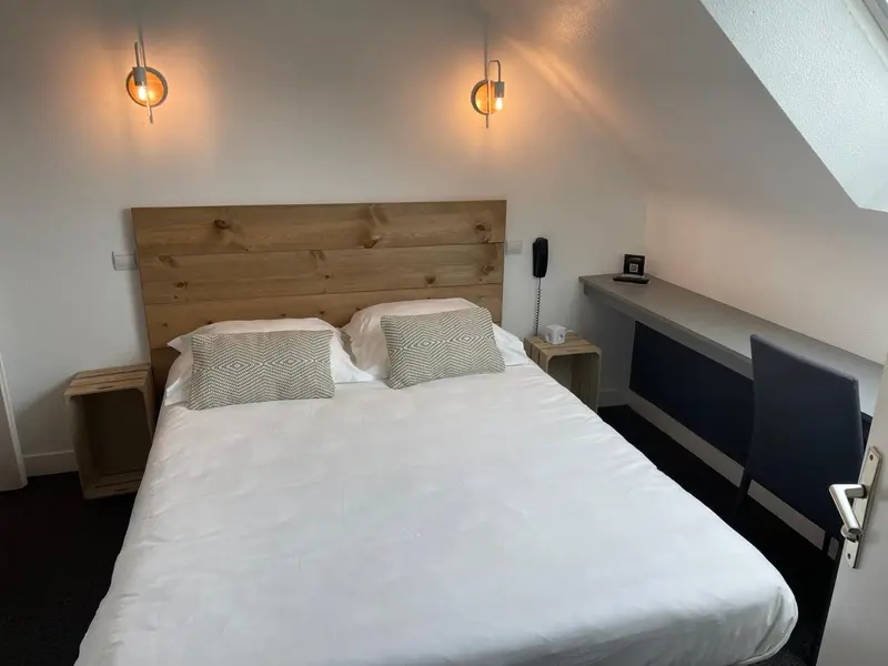 Une chambre lumineuse avec un grand lit et un espace bureau.