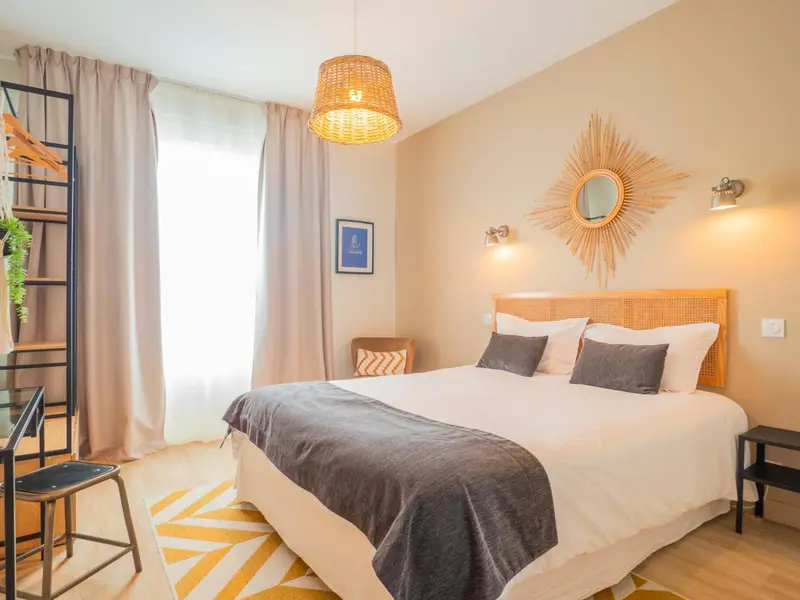 Une chambre lumineuse avec un lit double et une décoration murale ensoleillée.