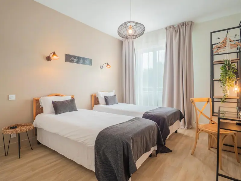 Une chambre lumineuse avec deux lits simples et une décoration sobre.