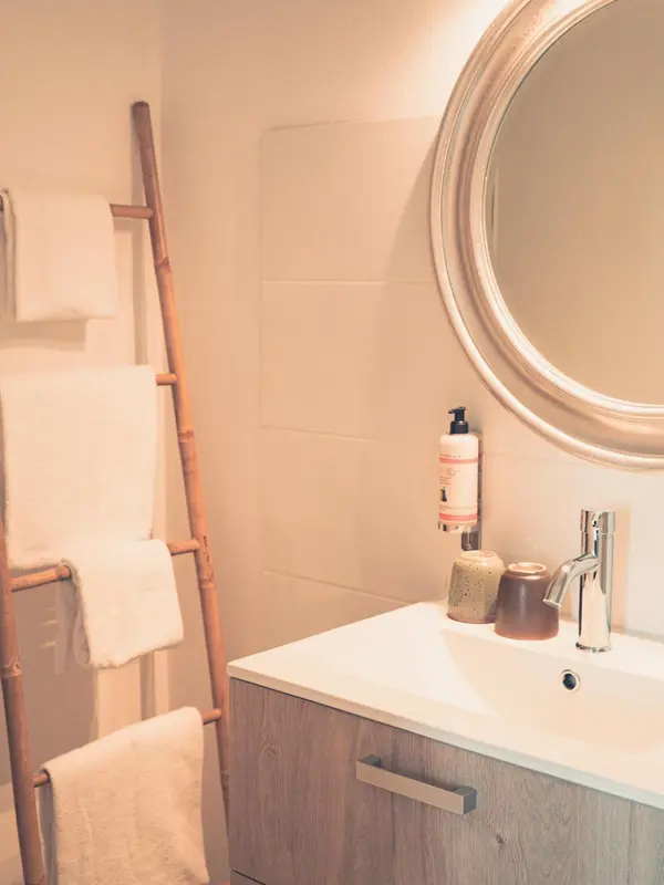 Une salle de bain lumineuse avec un meuble vasque et une échelle porte-serviettes en bambou.