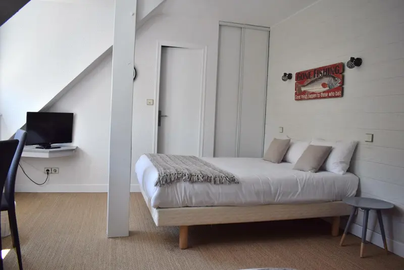 Une chambre lumineuse avec un lit et un téléviseur mural.