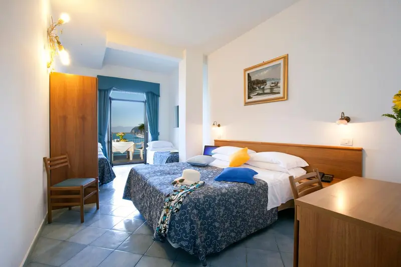 Chambre lumineuse avec un grand lit et un accès à un balcon.