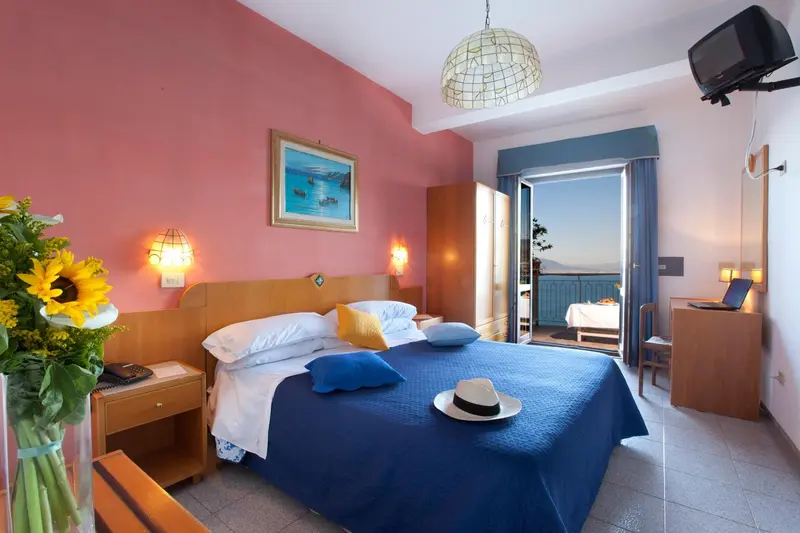 Une chambre lumineuse avec un grand lit et un accès à un balcon.