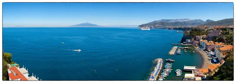 Vue panoramique sur la mer et la côte rocheuse avec des bâtiments colorés.