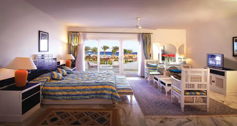 Une chambre lumineuse avec un grand lit donnant sur une vue mer.