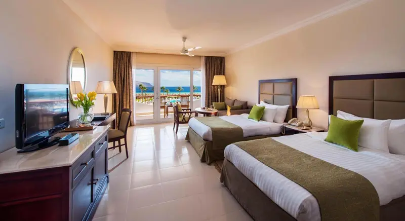 Chambre lumineuse avec deux lits et vue sur la mer.