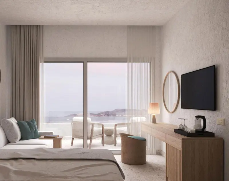 Chambre lumineuse avec vue sur la mer depuis une grande baie vitrée.