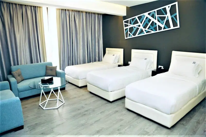 Chambre avec trois lits simples et un canapé bleu.