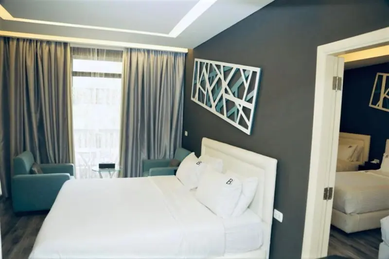 Une chambre lumineuse avec un grand lit et un fauteuil turquoise.