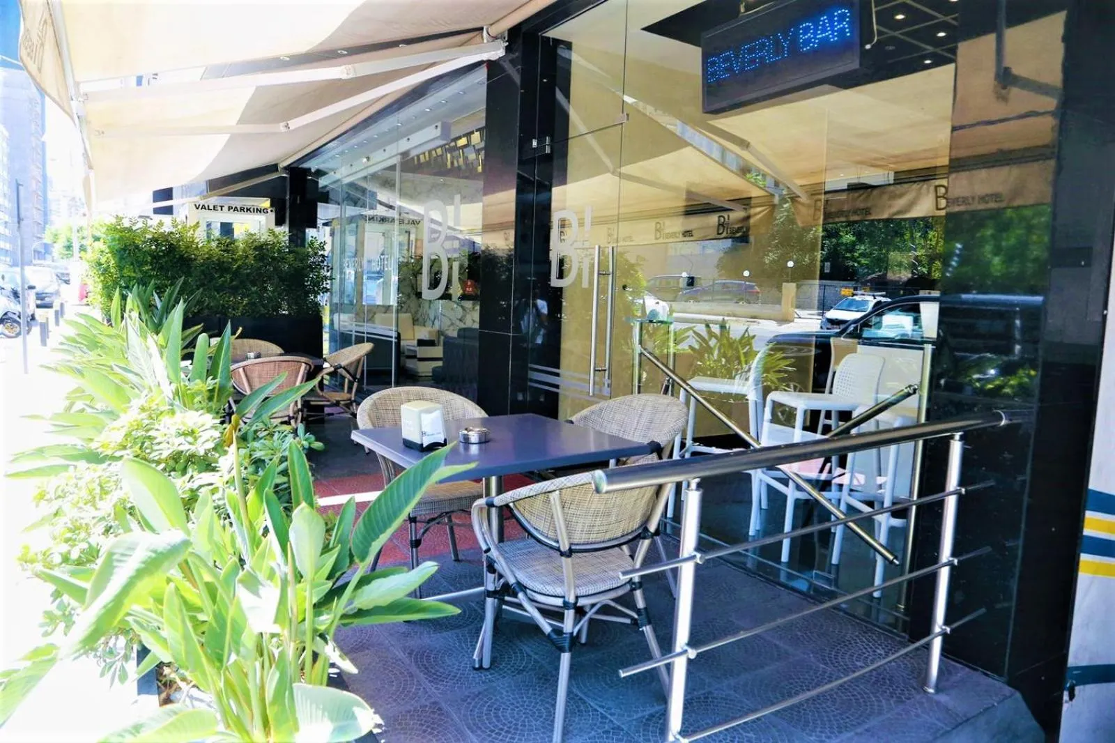 Terrasse de bar avec tables et chaises devant une façade vitrée.
