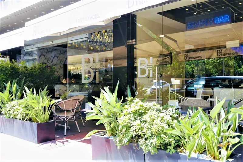 Façade d'un hôtel moderne avec végétation et mobilier d'extérieur.