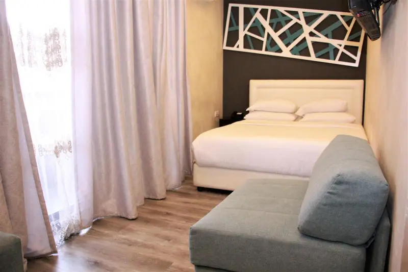 Une chambre lumineuse avec un grand lit et un coin salon.