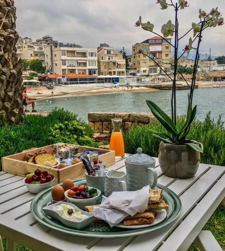 Un petit-déjeuner est servi sur une table en extérieur avec vue sur la mer et la plage.