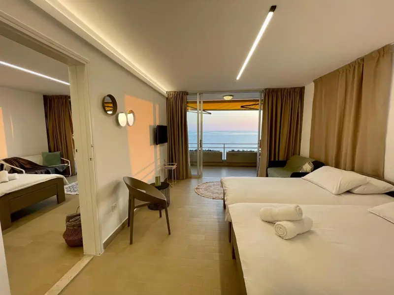 Une chambre lumineuse avec deux lits et un accès à une terrasse ensoleillée.