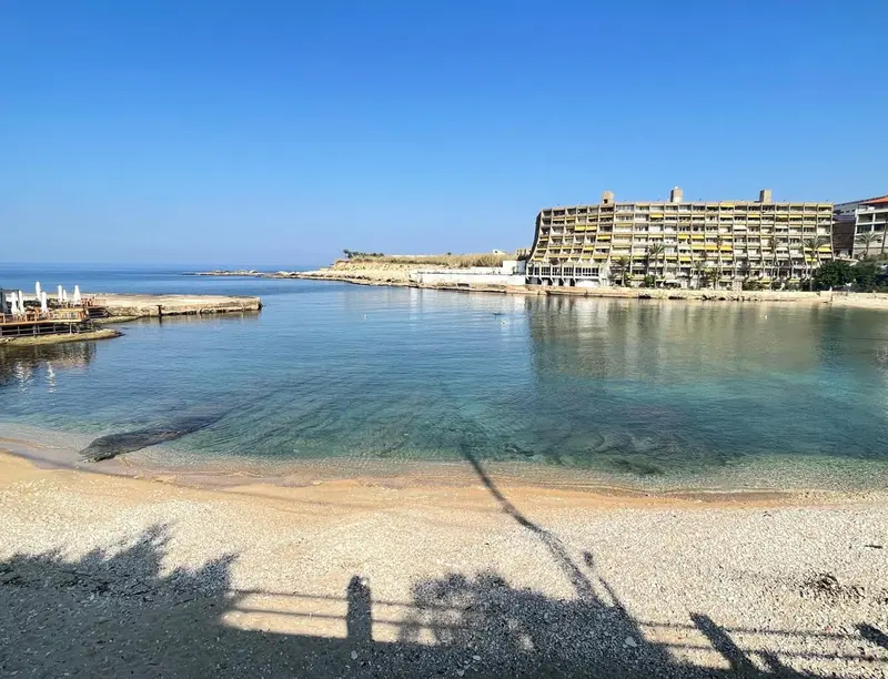 Vue d'une crique abritée avec une plage de galets et un bâtiment en bord de mer.