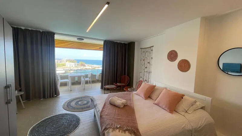 Chambre lumineuse avec un grand lit et une vue sur la mer.