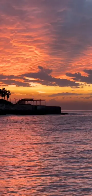 Coucher de soleil sur l'océan avec une jetée au premier plan.