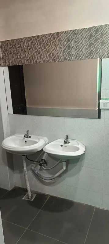 Deux lavabos blancs sont installés dans une salle de bain carrelée.