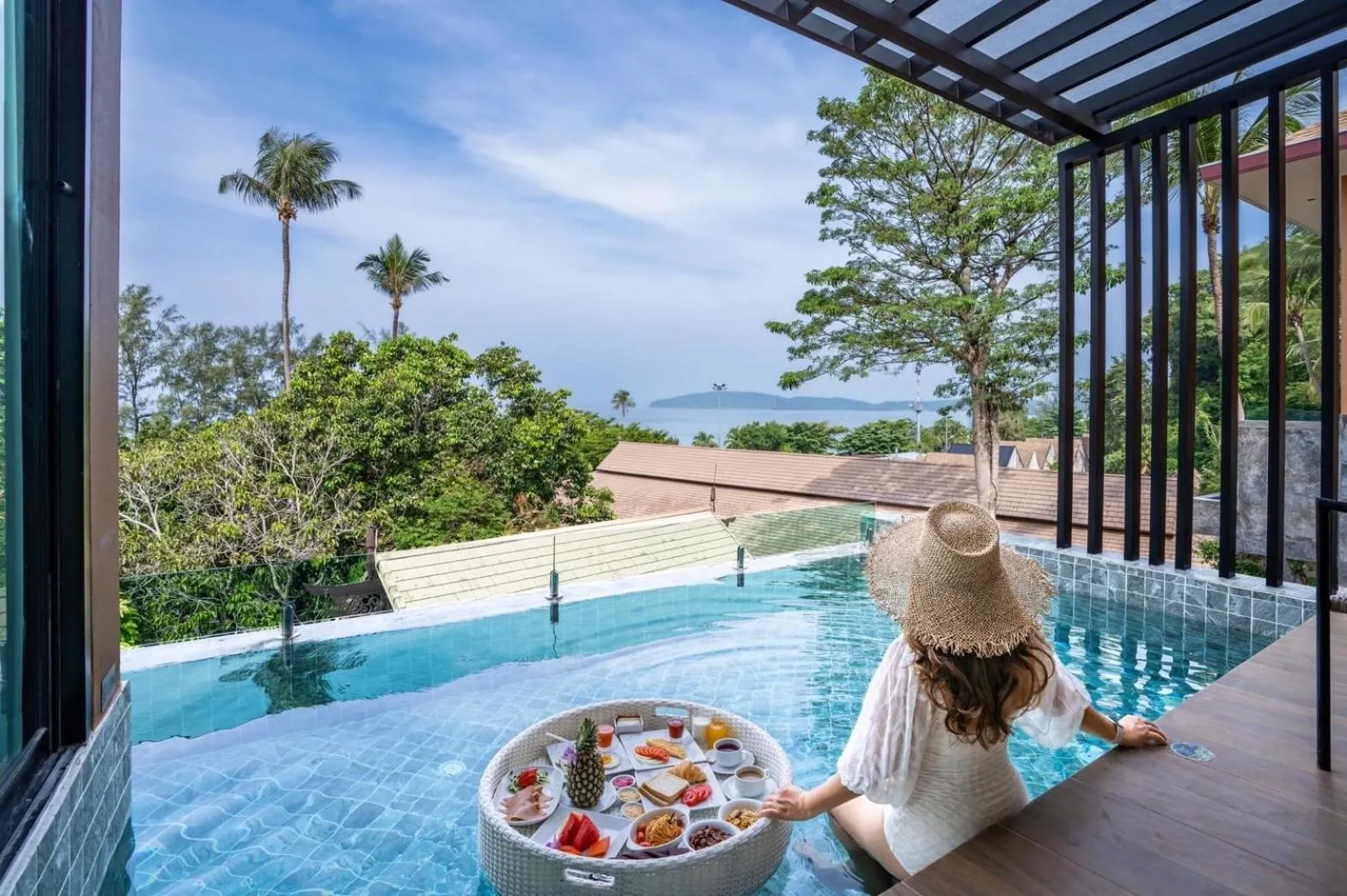 Une personne est assise au bord d'une piscine avec un plateau de nourriture.