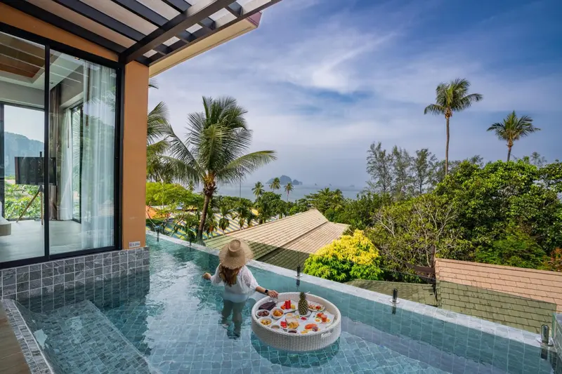 Une personne se détend dans une piscine privée avec un plateau de fruits.