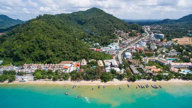 Vue aérienne d'une plage bordée de bâtiments et d'une végétation luxuriante.