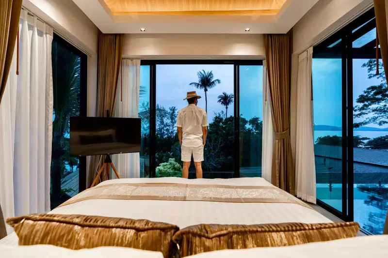 Une chambre lumineuse avec un grand lit donnant sur une vue tropicale.